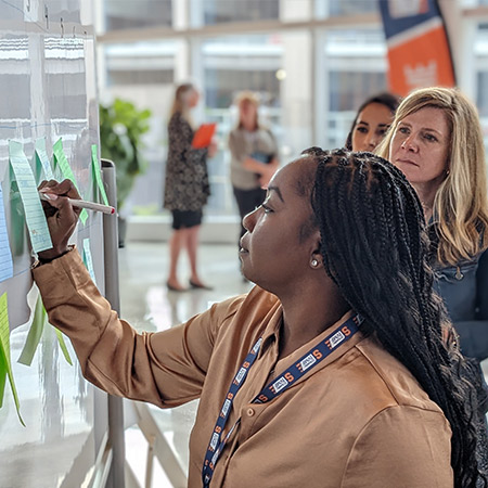 A veteran attending a community event writing her ideas on a white board. 