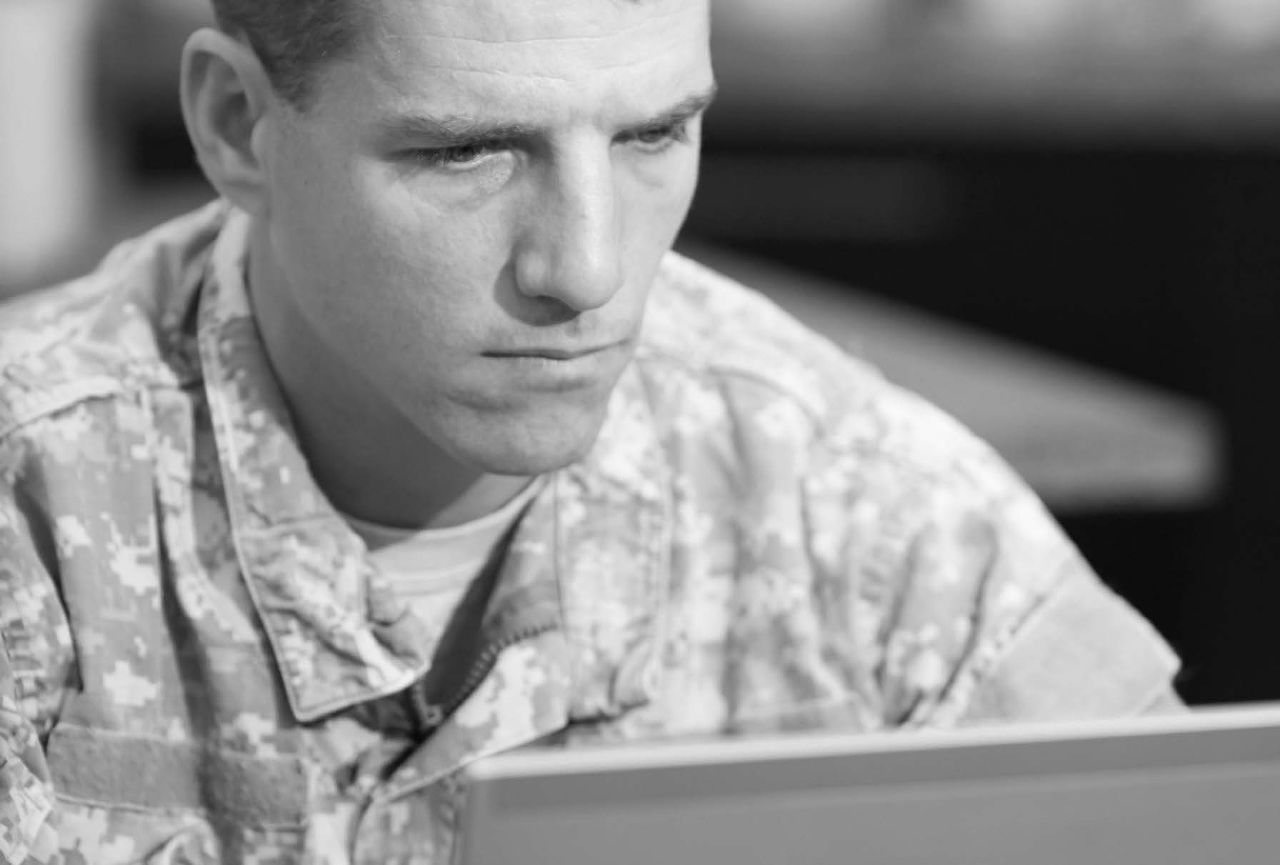 Solider looking intently at computer in fatigue uniform