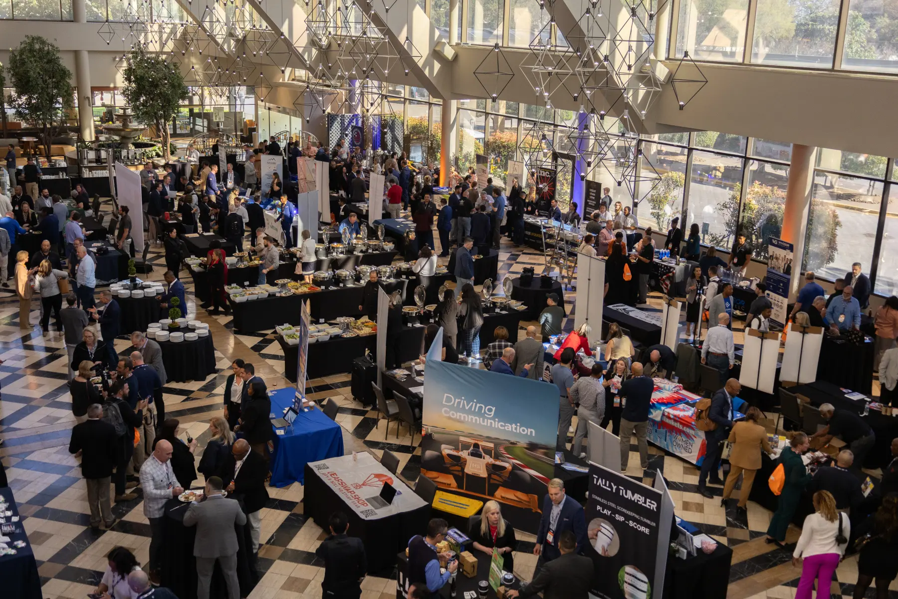 Overhead view of the crowded expo floor of the EDGE showcase event. Attendees browse the rows of display tables filling the large open room.