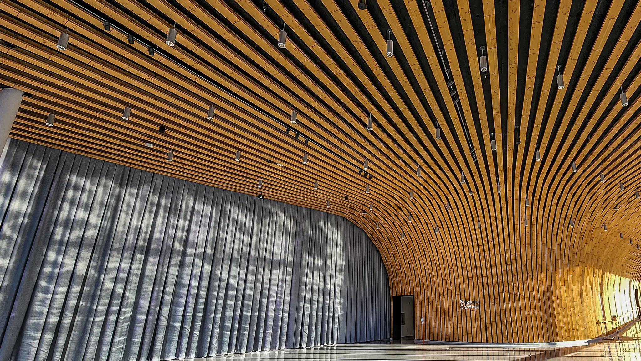 Wide view of the Bisignano Grand Hall facing the wooden architectural design that extends from the floor, up the wall, and across the ceiling.