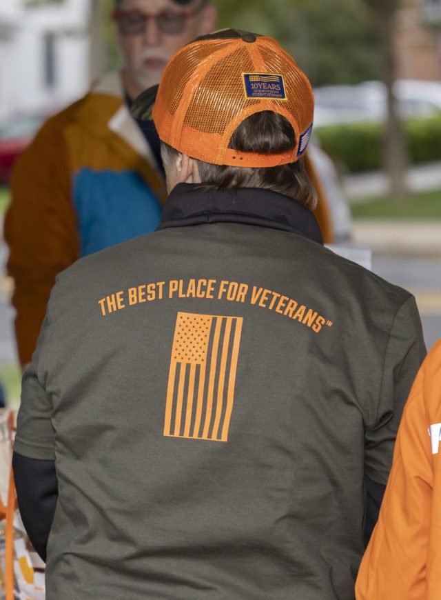 Back of a man wearing a jacket with graphic of an American flag with text that reads: The best place for Veterans.