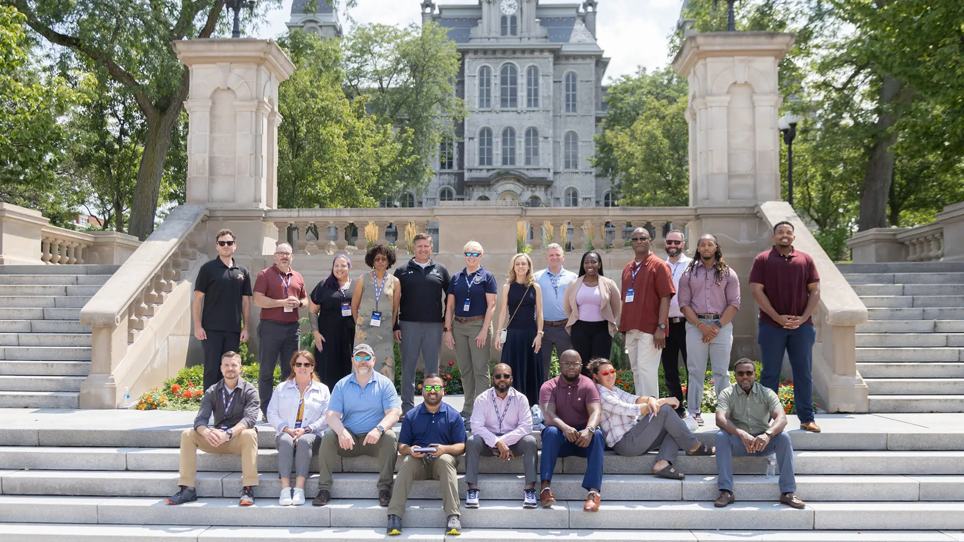 A group of 21 EVB SU team members pose on the stairway leading up to the clock tower at SU.