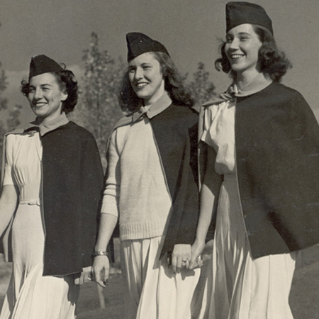 Vintage photo of 3 women in military nurses uniforms standing shoulder to shoulder.