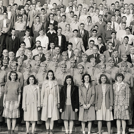 Vintage photo of a large group of men and women standing tightly together on the stairs at SU.