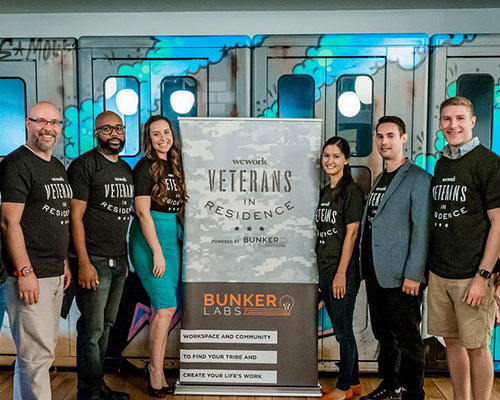 2 women and 4 men wearing Veterans tee shirts stand with a Veterans in Residence stand-up banner.