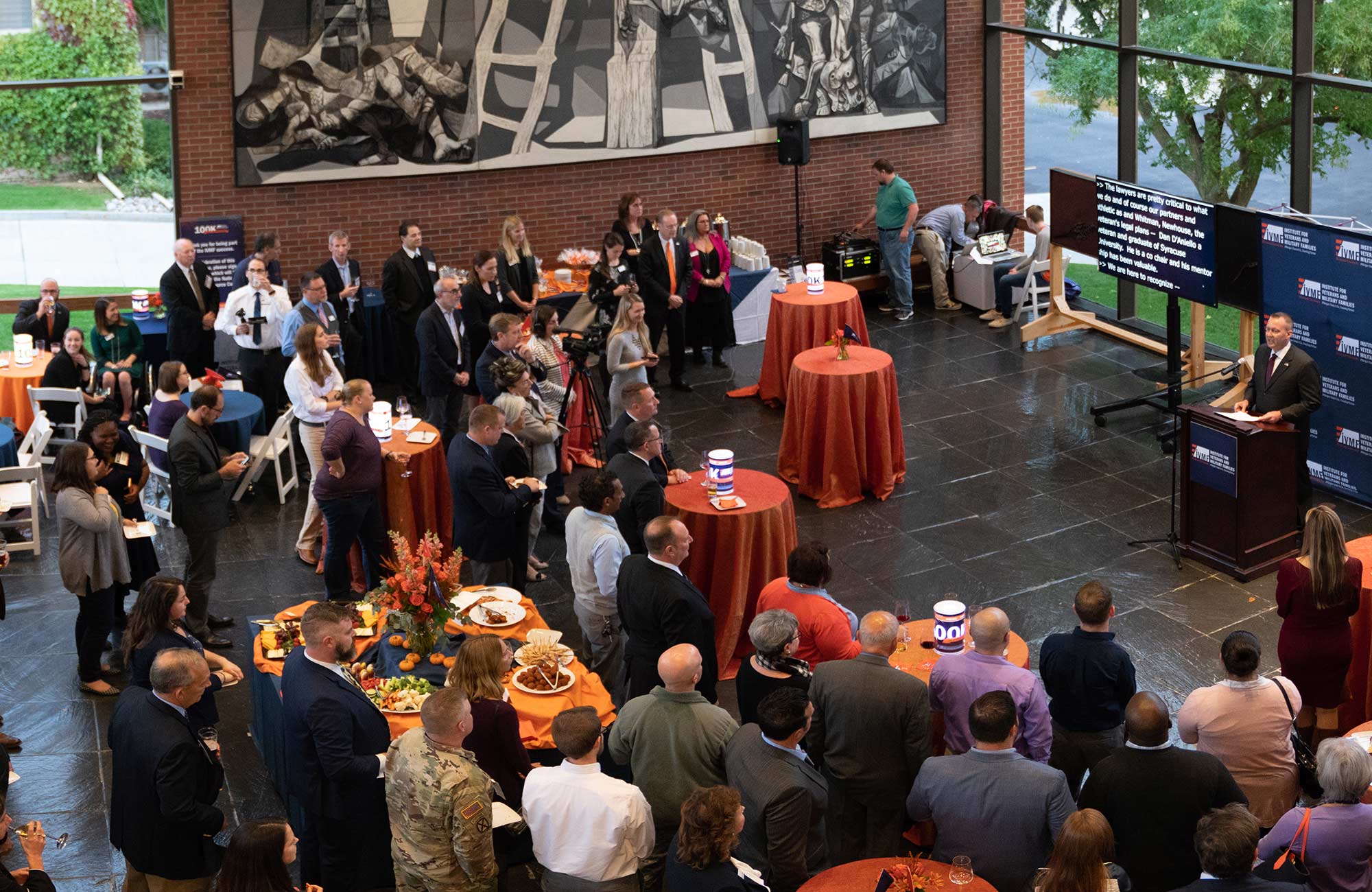 A large crowd gathered around a presenter in a large open room