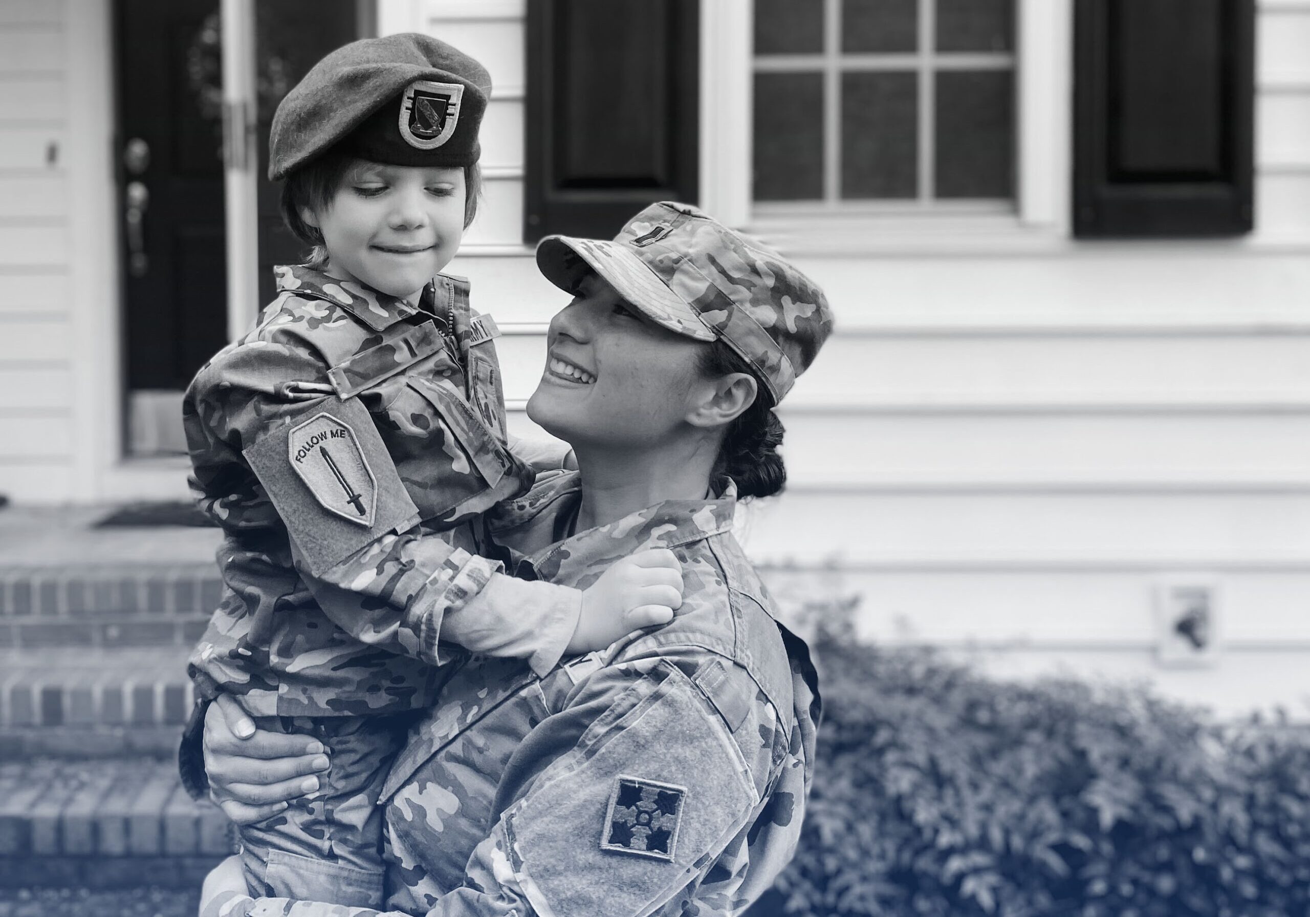 Women solider holding her son in a child military uniform
