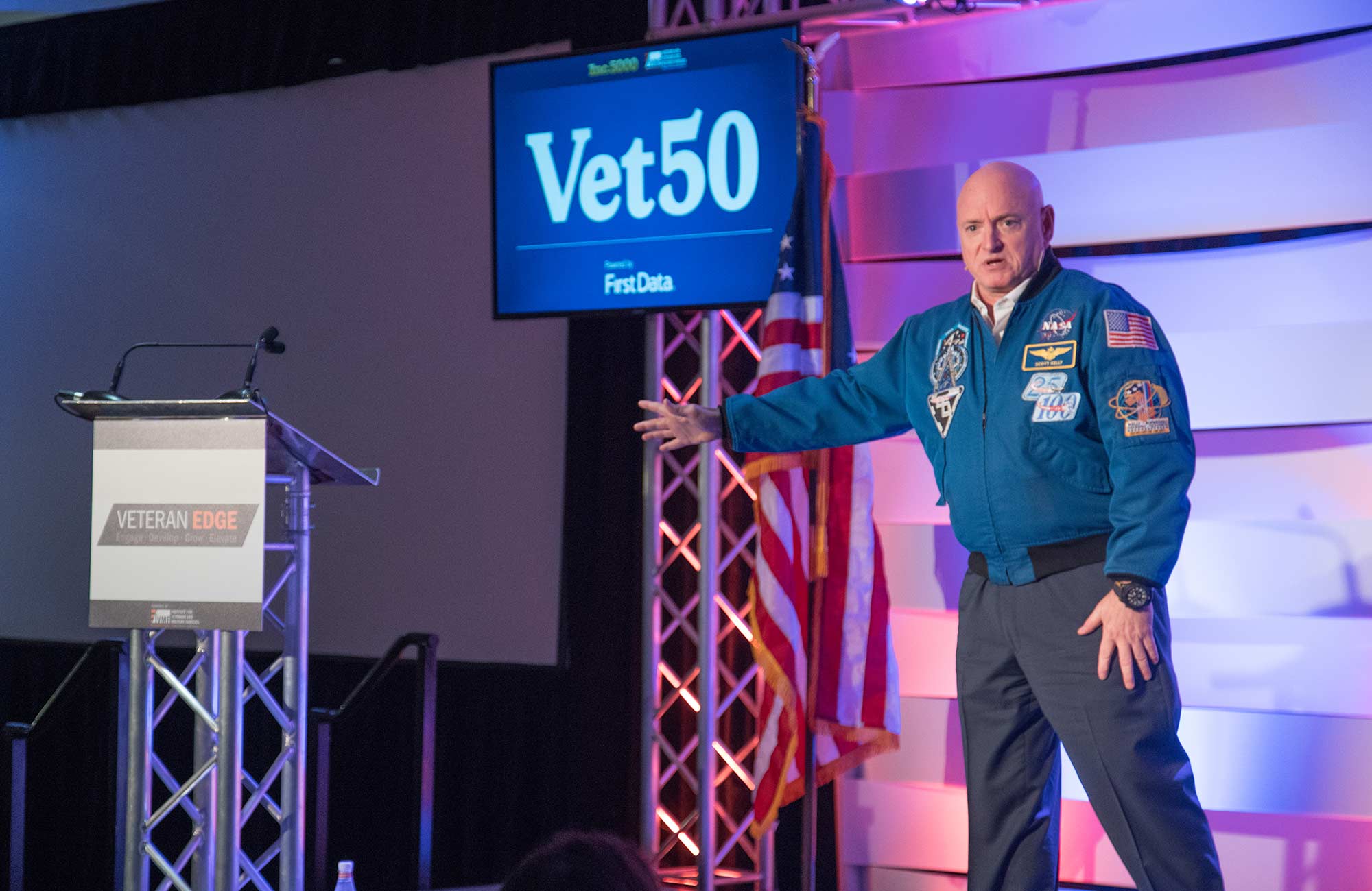 Scott Kelly speaks to the crowd from a stage at the Vet50 event
