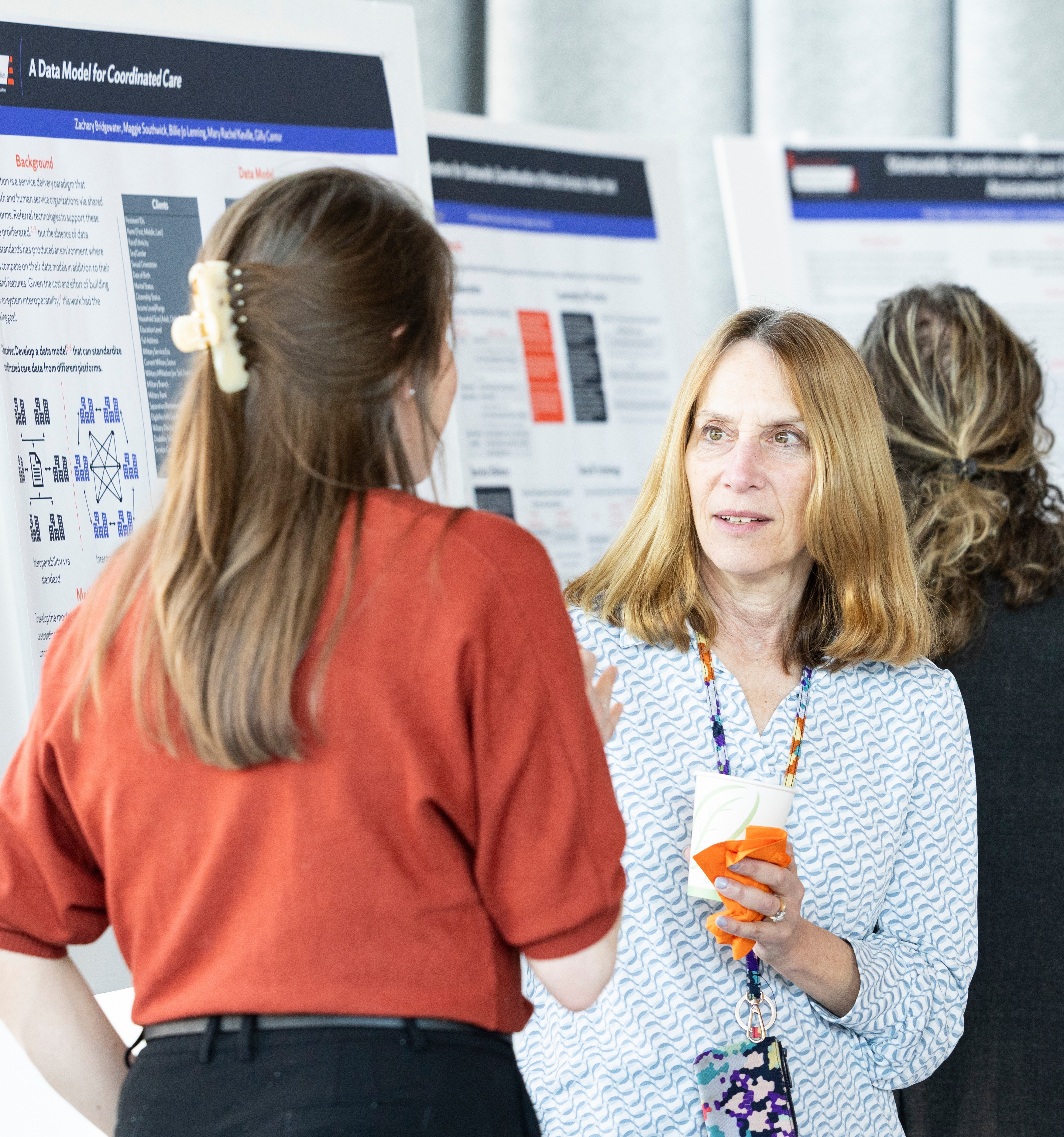Two people speaking in front of white board exhibiting data.