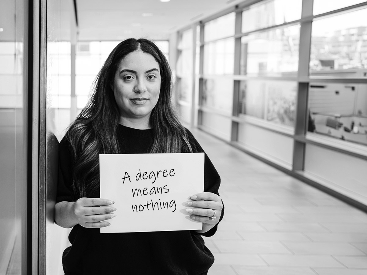 Military spouse holding sign saying "a degree means nothing"