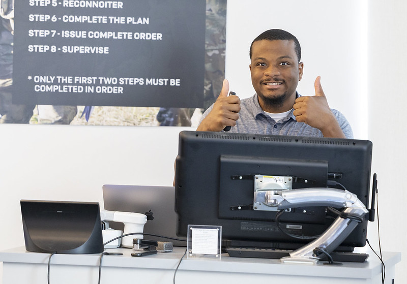 IT tech giving thumbs up behind a computer. 
