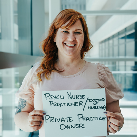 Military spouse holding a sign that says psyc u nurse practionar (doctor of nursing) private practice owner