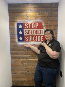 Belverly standing in front of a Stop Soldier Suicide sign. 