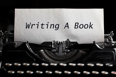 Type writer with "writing a book" on the paper