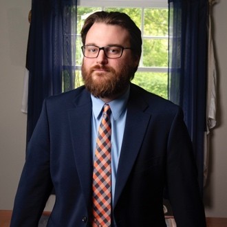 Headshot of Addisson ODonnell wearing a blue suit in front of a window.