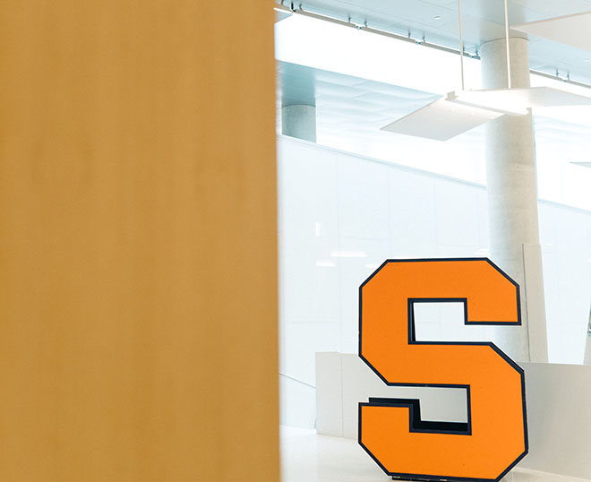 Syracuse S in front of a light background in the atrium of Dineen Hall, mainly decorative.