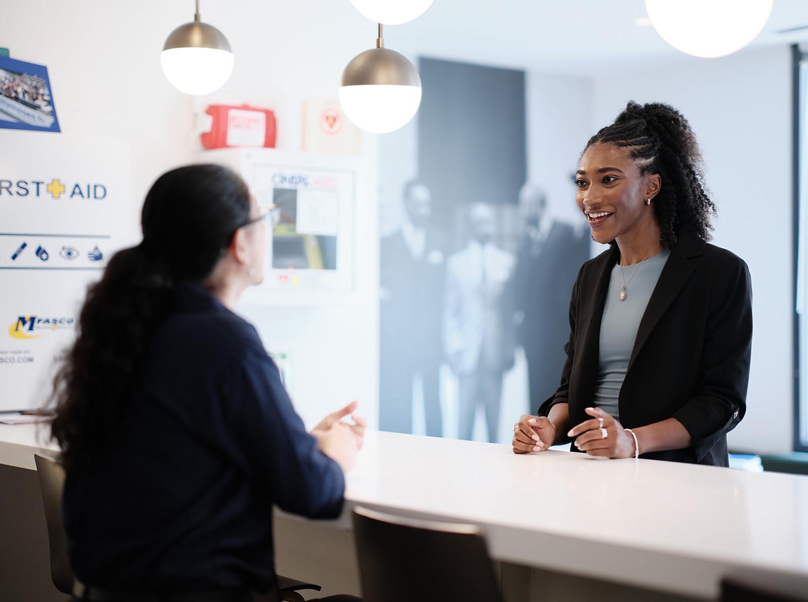 Student speaks to another person while standing at a white desk in the lobby of the NAACP in Washington DC