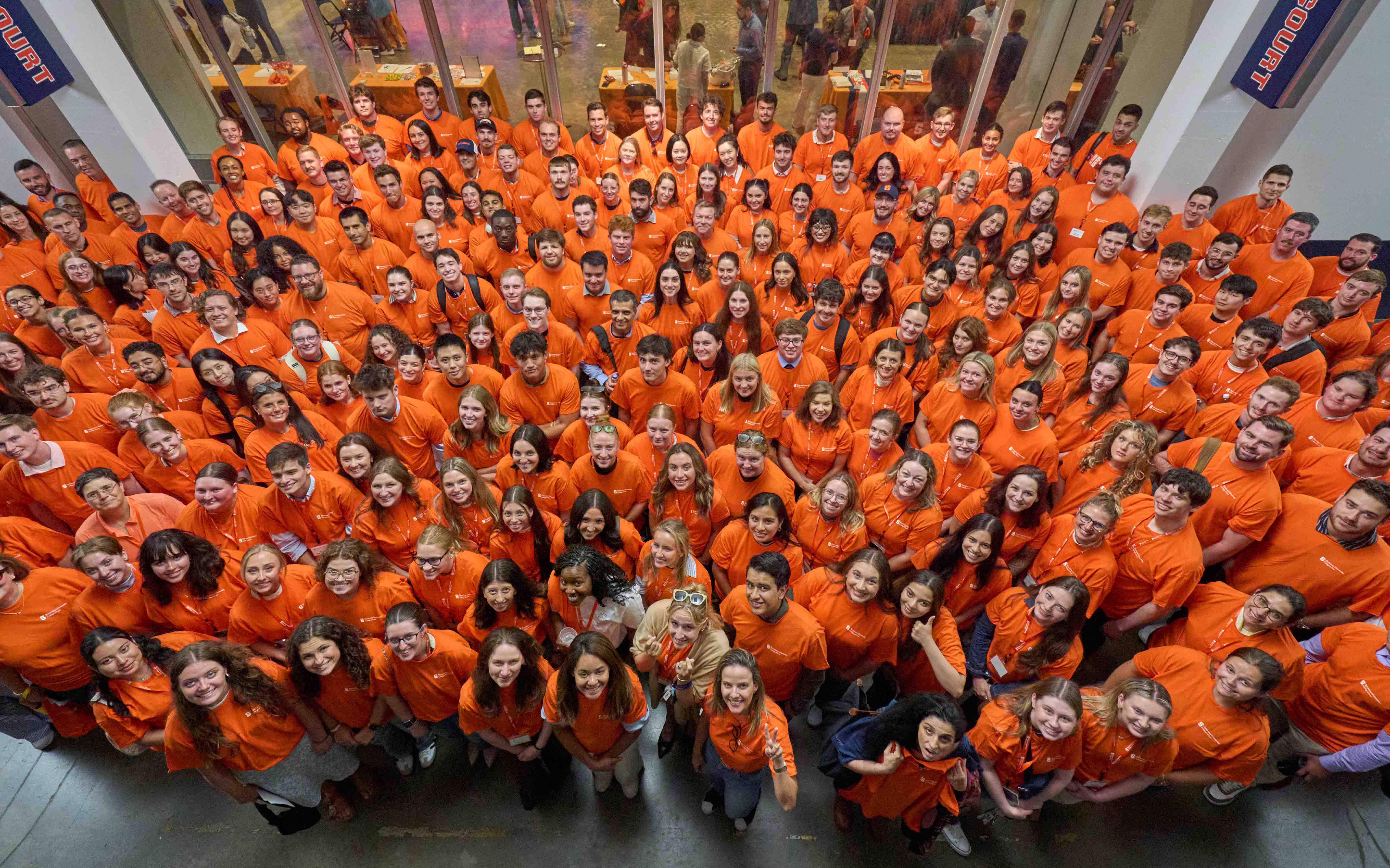 Aerial image of full incoming class, all wearing orange shirts.