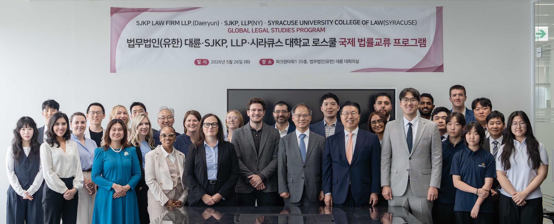 Group of students stands in front of a sign welcoming them to the Daeryun Law Firm.