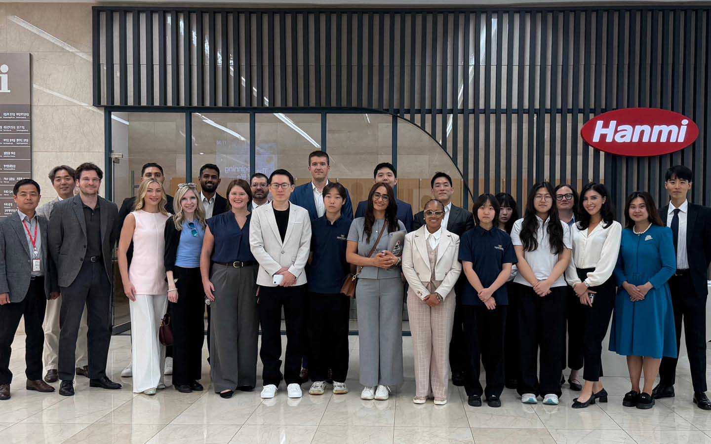 Group of students stands in front of Hanmi logo at the firm's building. 