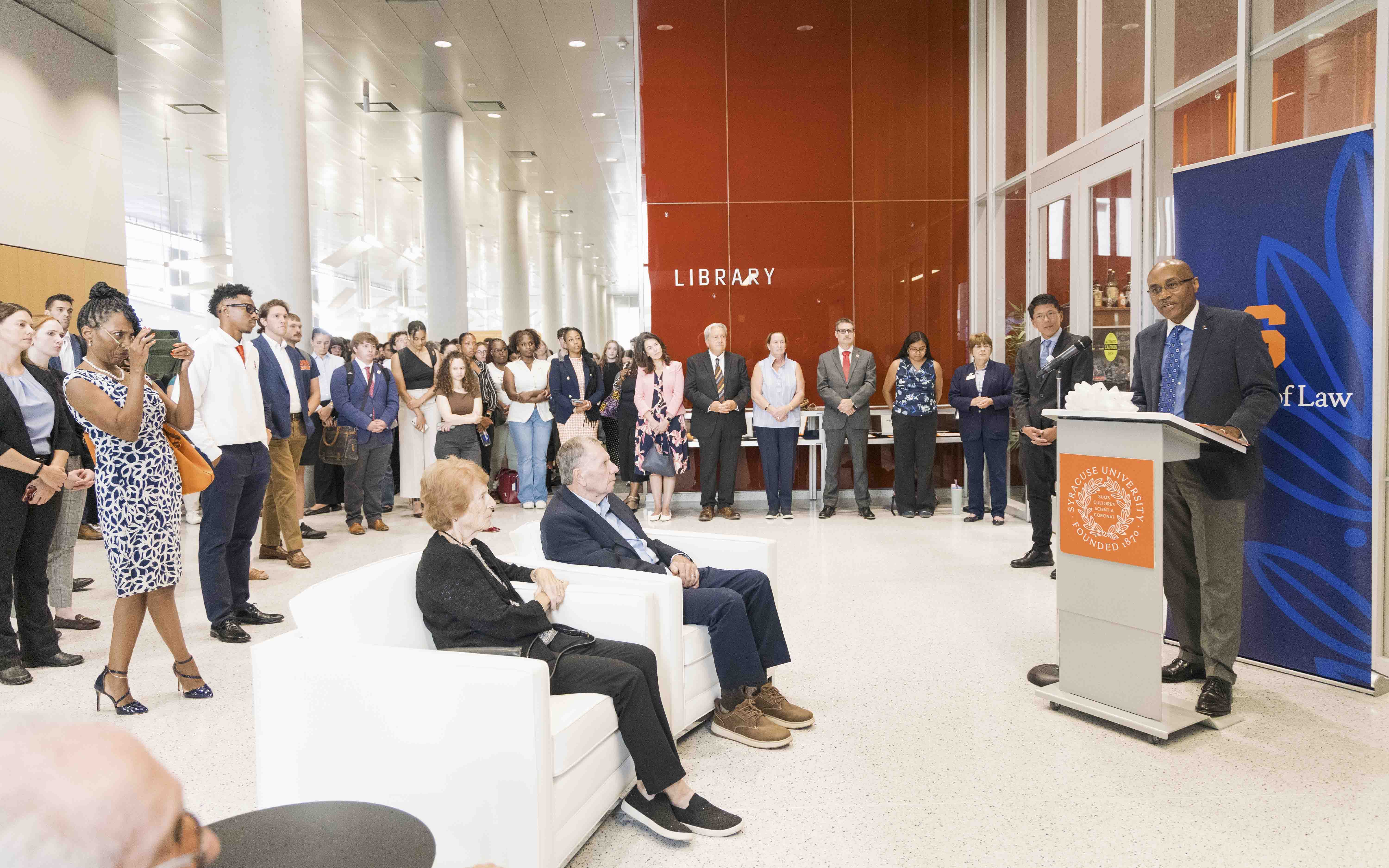 Judge Thompson speaks from the podium to a crowd full of people in the Atrium of Dineen Hall.