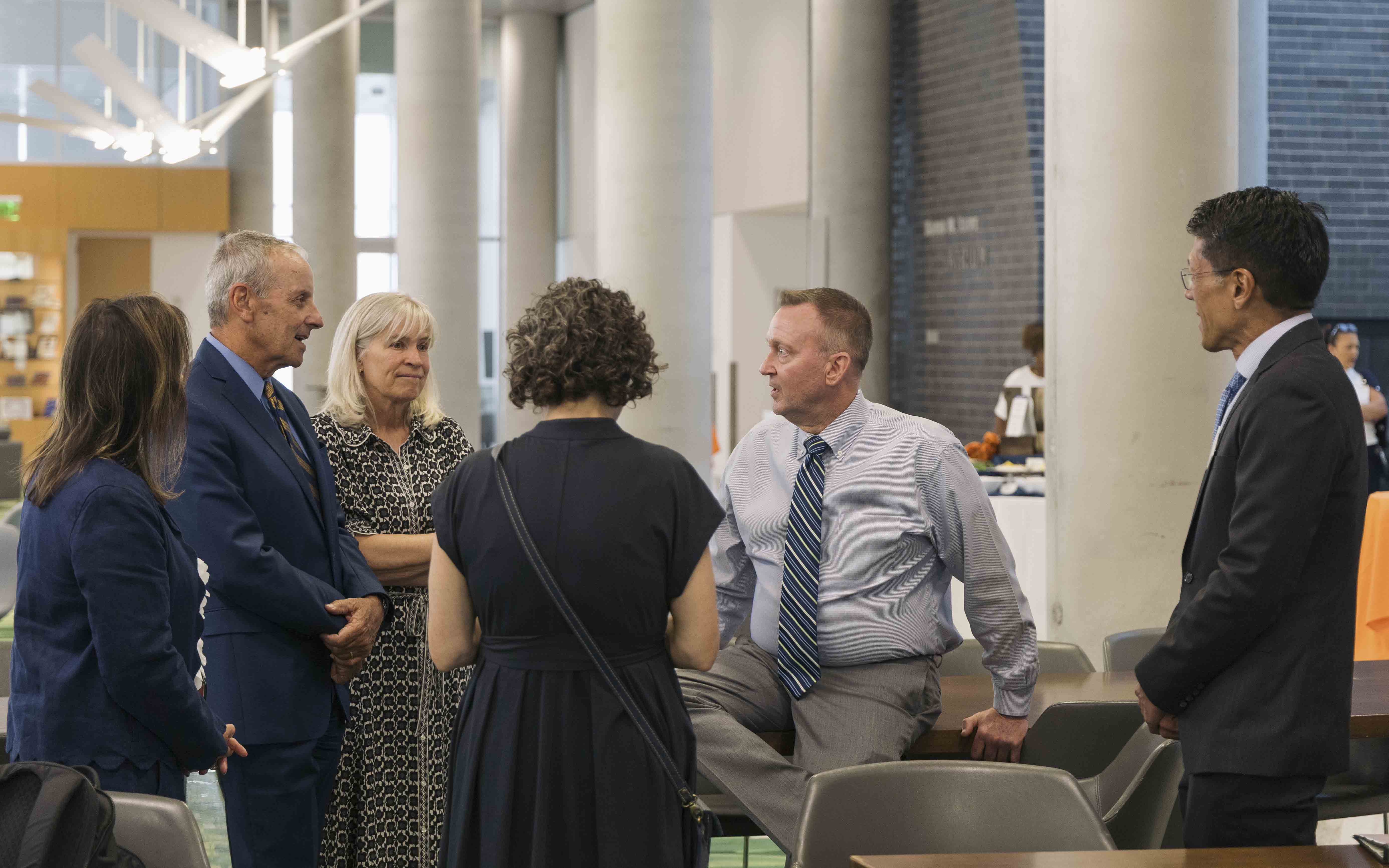 Chancellor Haynie sits with a group of five people talking in the Atrium of Dineen Hall.