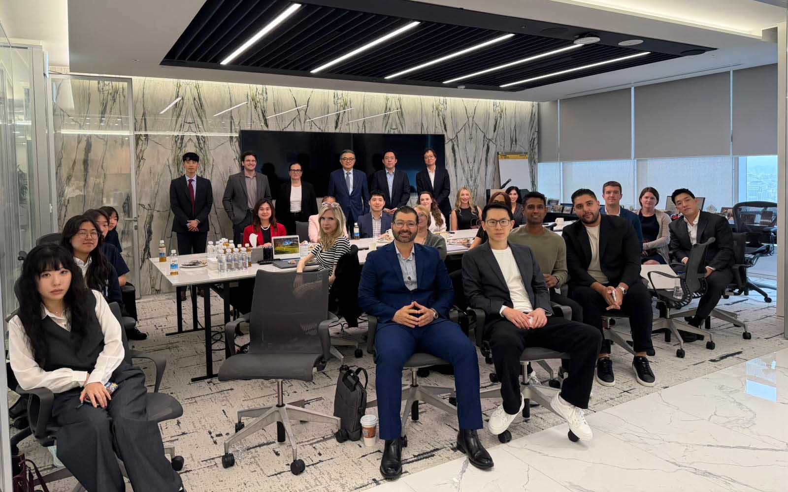 Group of students sits at a table in DLA Piper in front of a marble wall.