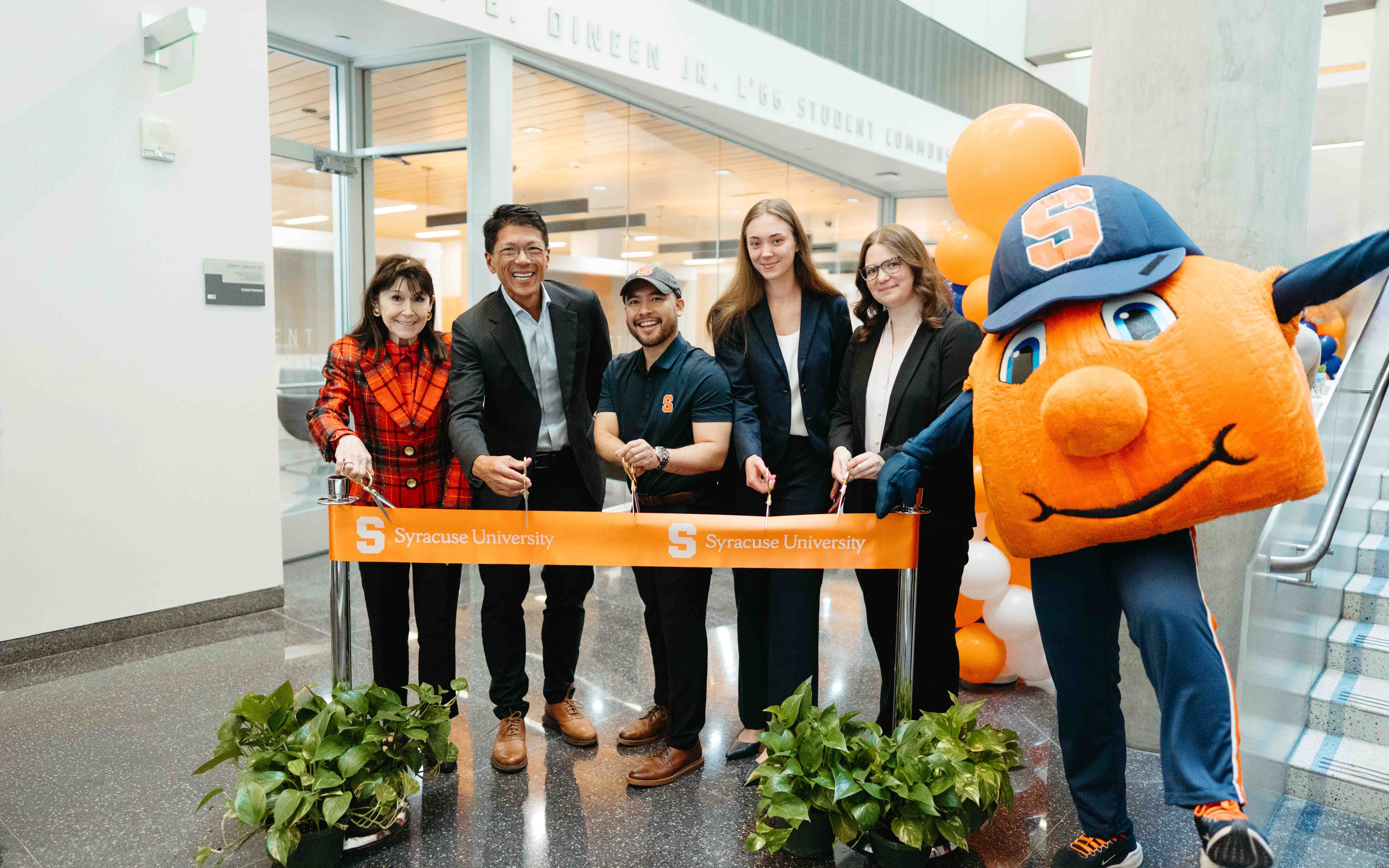 Ribbon cutting for the new Dineen Student Commons, featuring Otto the Orange and five people.