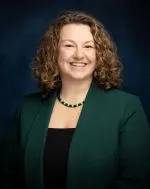 Headshot of young woman in dark green suit smiling