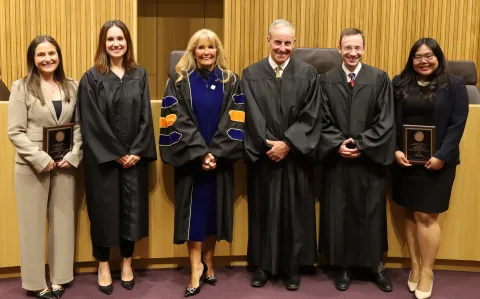 Six people standing wearing judicial robes or business attire.