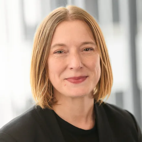 Woman with light hair in a dark top.