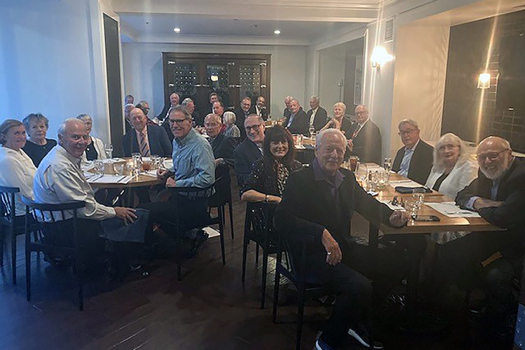 three tables full of people joined together at dinner celebrating their 50th law school anniversary and reunion