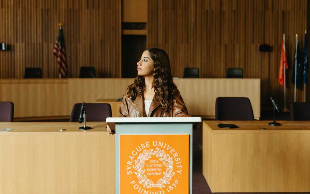 Maheen Asim at the podium in the courtroom looking out of the window