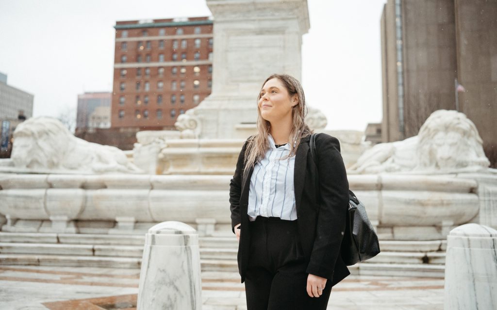 Carly looking off into the distance in front of a fountain