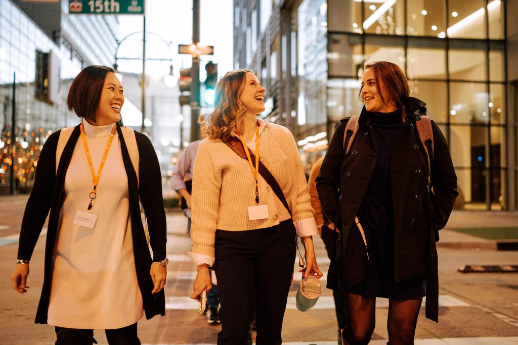 three women smile and talk to each other outside on the streets of Denver, CO