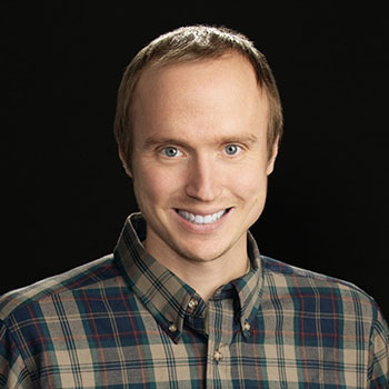 ramsey hilton smiles at the camera in front of an all black background