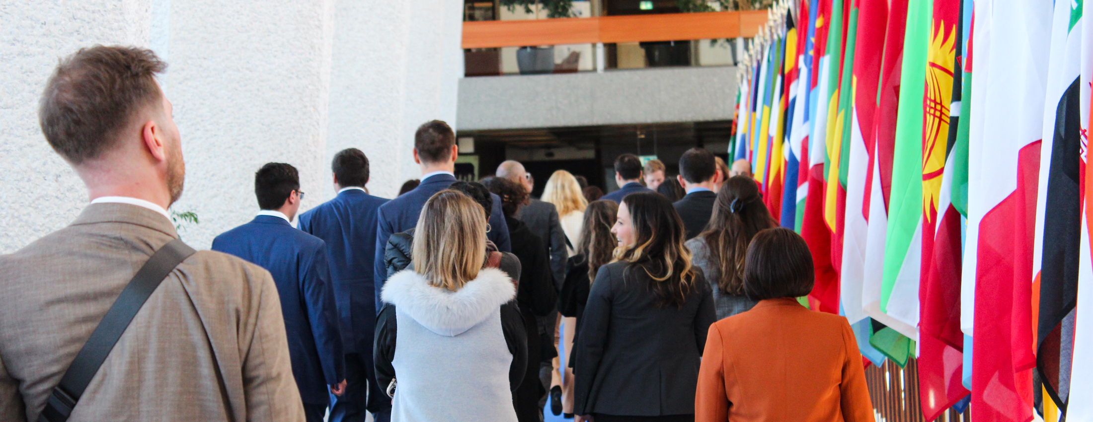 Students tour a facility with large colorful flags on the right side