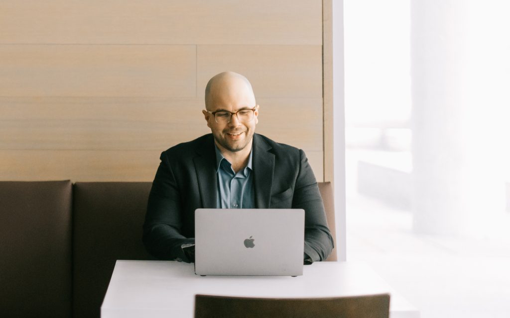 Joseph Creager sits at a laptop and smiles