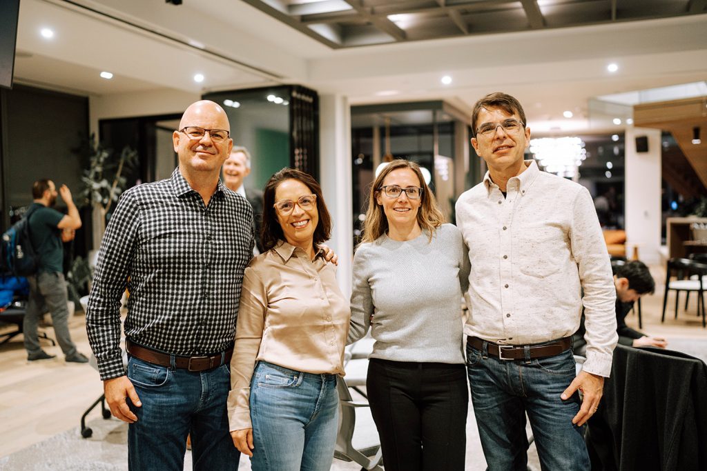 four LLM students smile at the camera, standing in a brightly lite room at a networking event