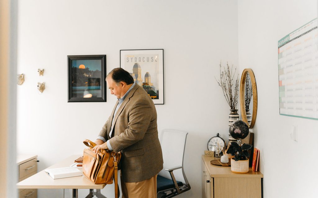 John Lawrence looks in his briefcase in an office.