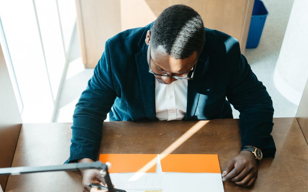 Linton looks down at a folder while sitting at a desk