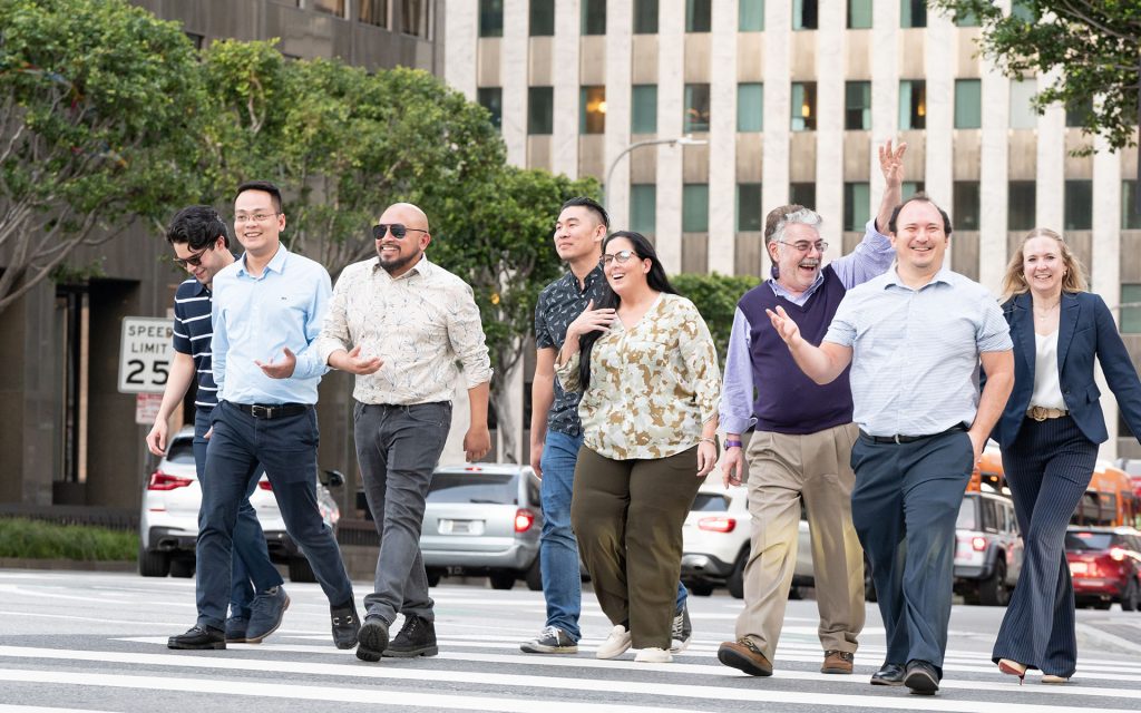 Group of JDi students walk across a crosswalk laughing and talking with Professor Levy