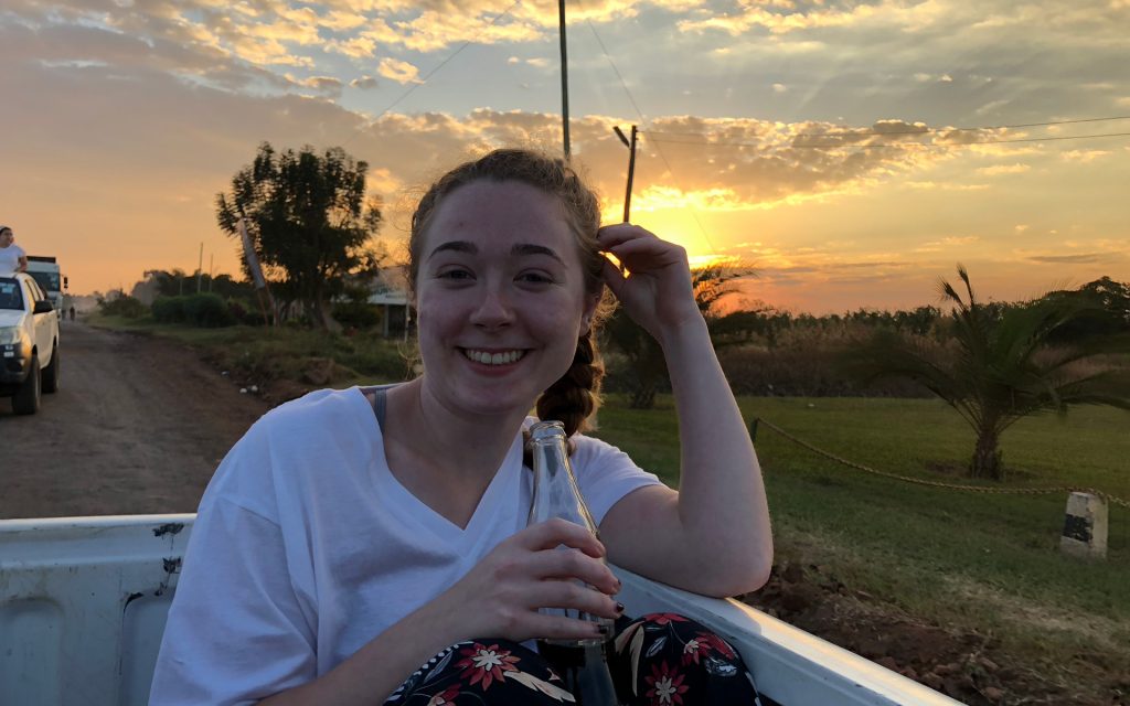 Meghan Wright sits in a truck drinking a soda while outside on a mission trip 