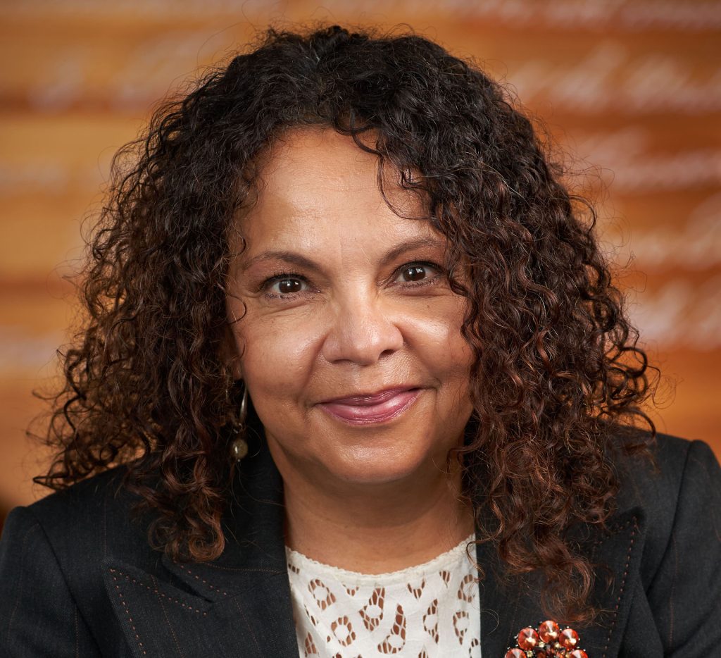 Headshot of Suzette Melendez smiling at the camera in front of a wall in the Syracuse Law Library