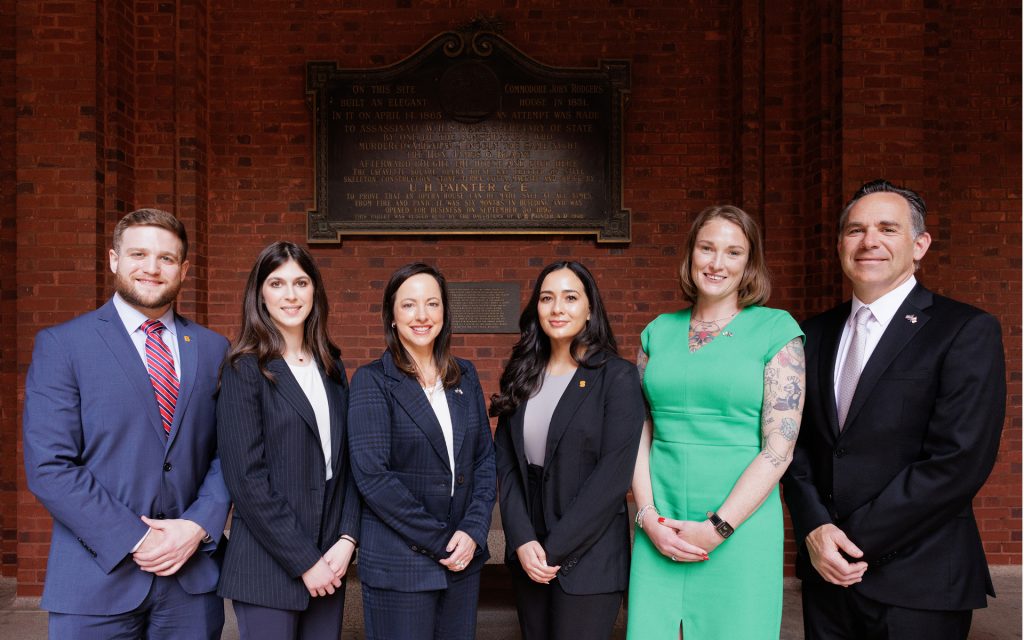 Students and faculty standing in a line in front of a brick wall
