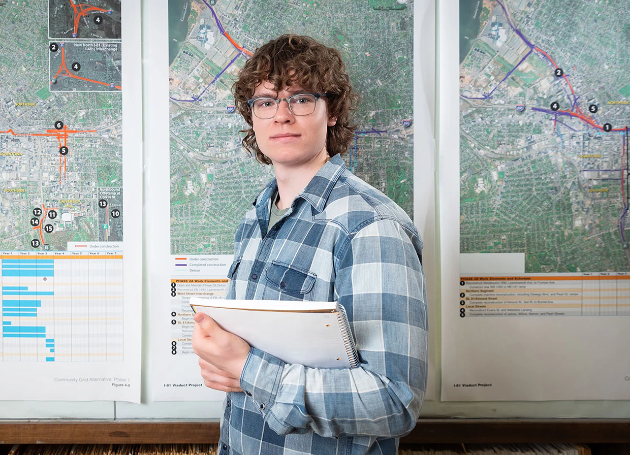 Person holding a notebook in front of maps.