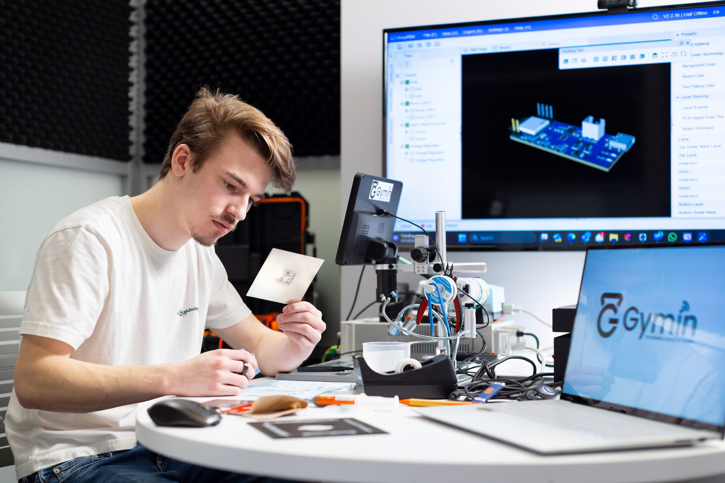 Tony Goncalves looking at a note card while working at a table with multiple computer monitors.