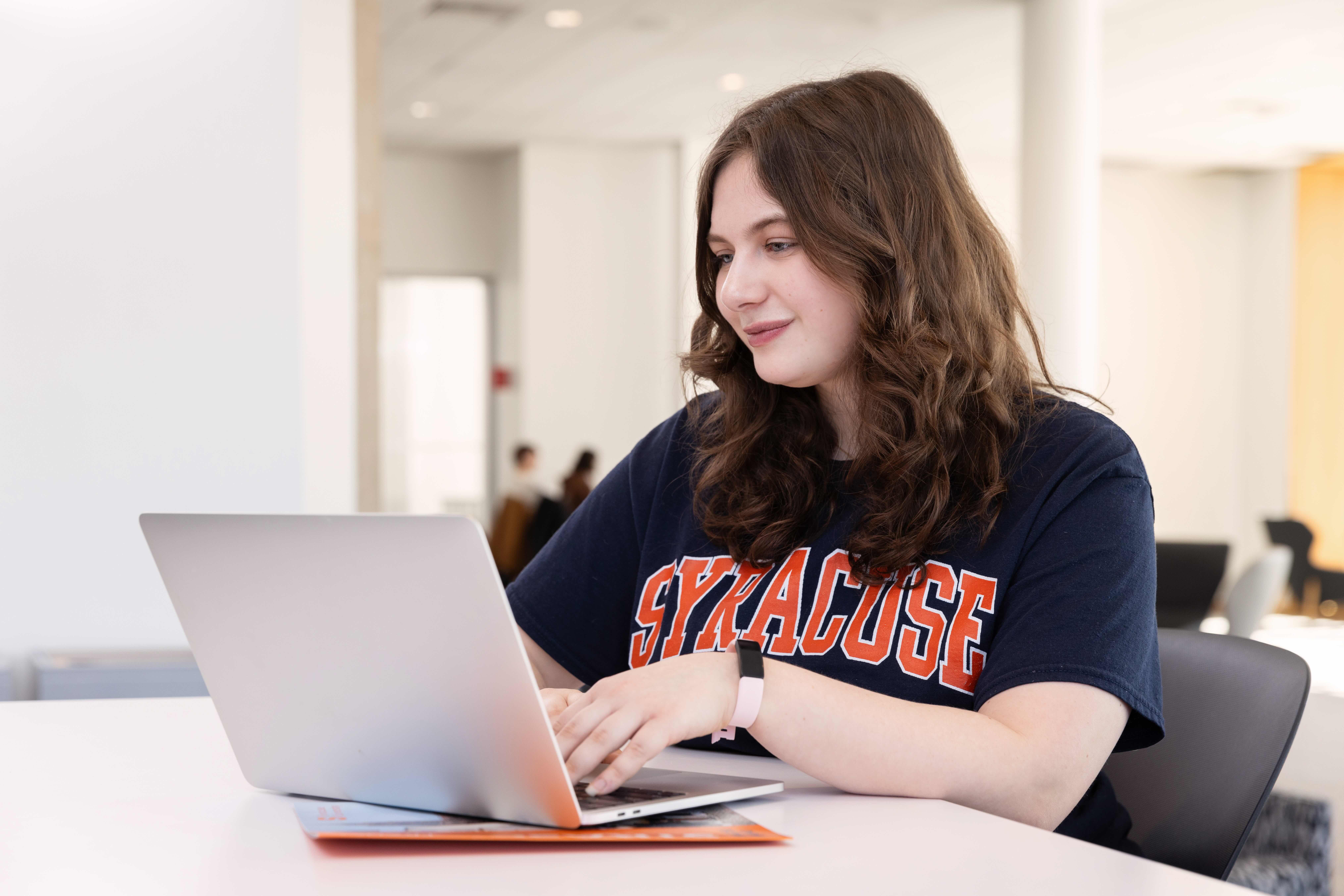 A student looking at a computer smiling. 