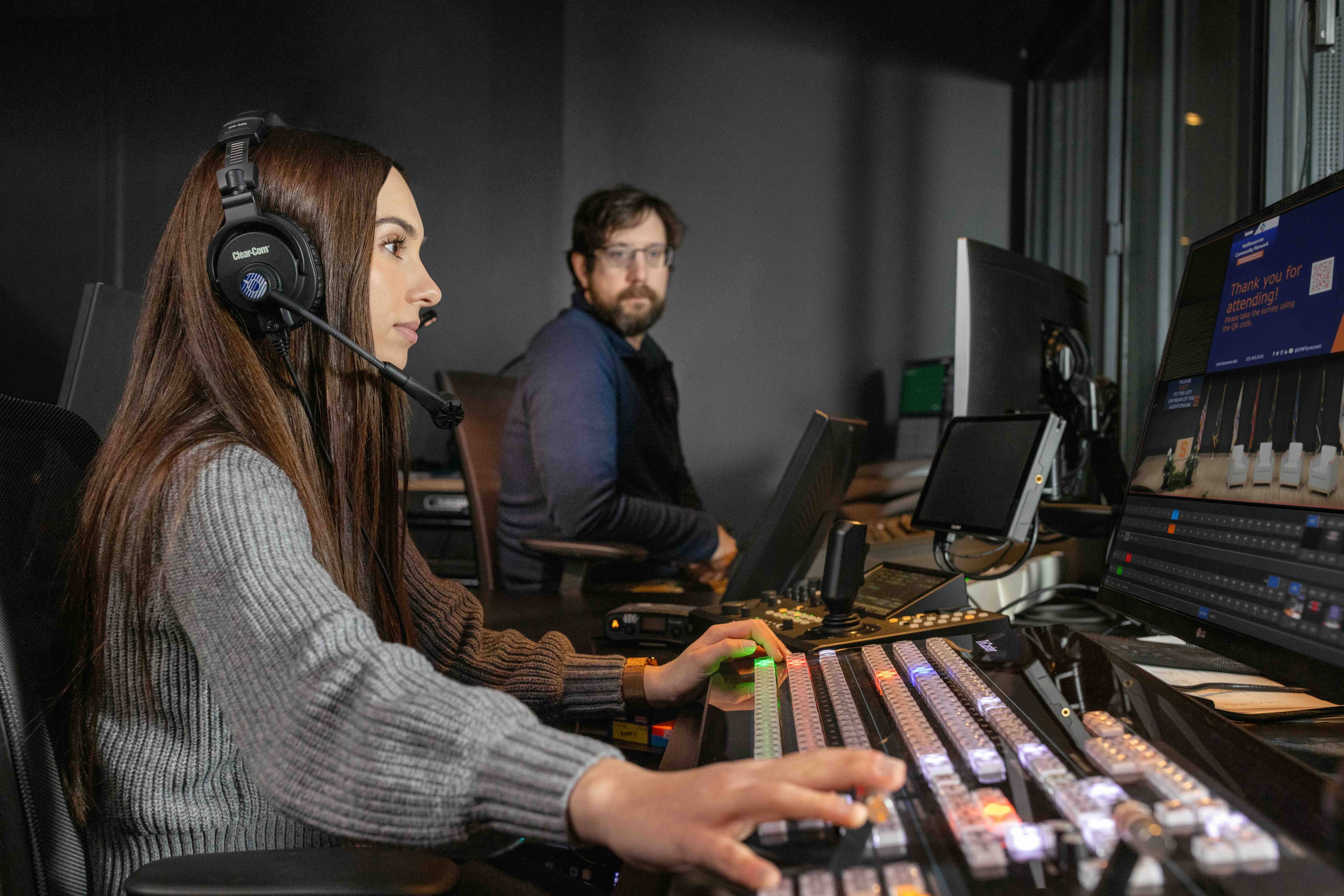 A student working on a computer with a headset on. 