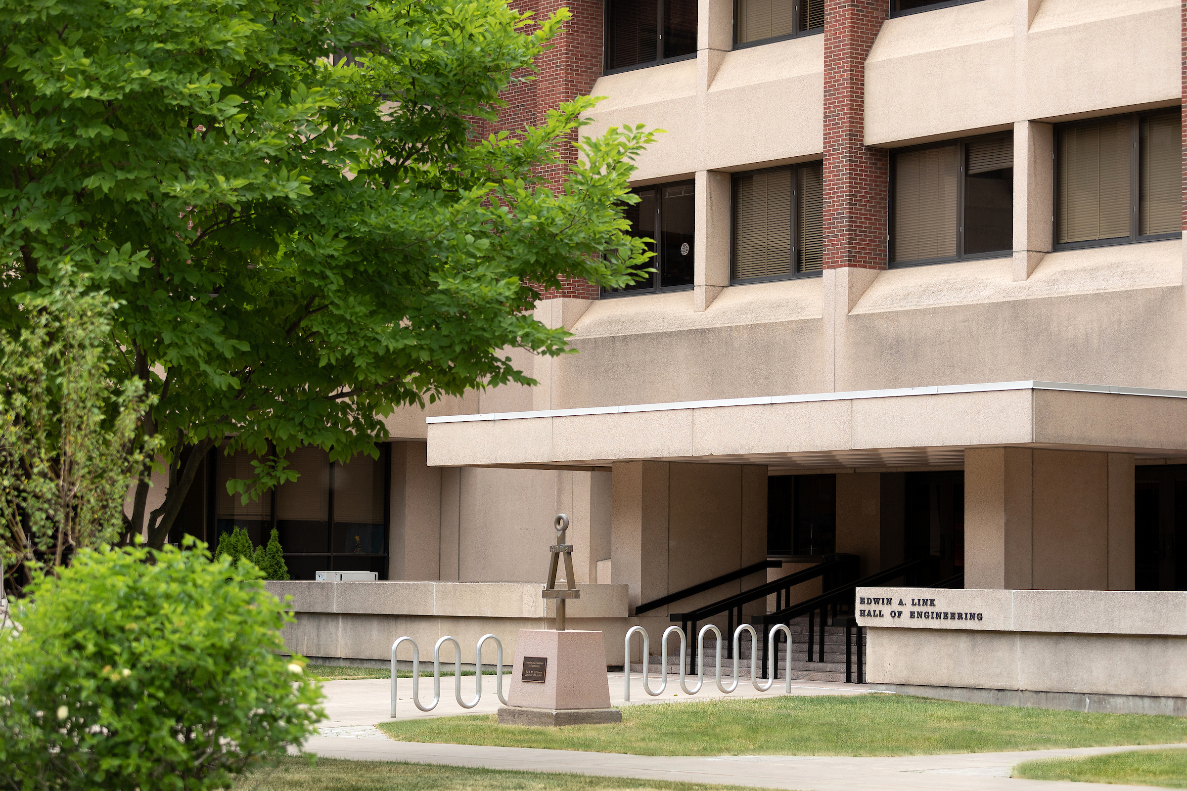 The south entrance of Link Hall takes up most of the frame with the left being taking up by trees and bushes. 
